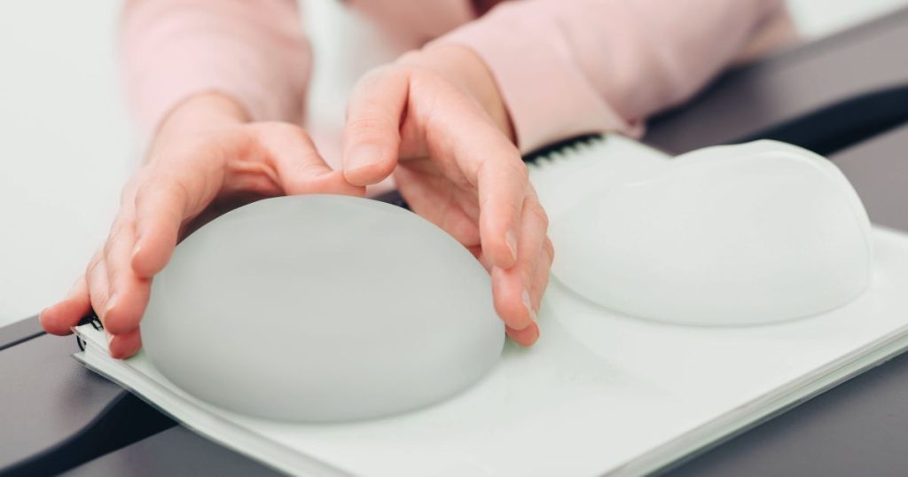 femeie care tine in mana implanturi mamare